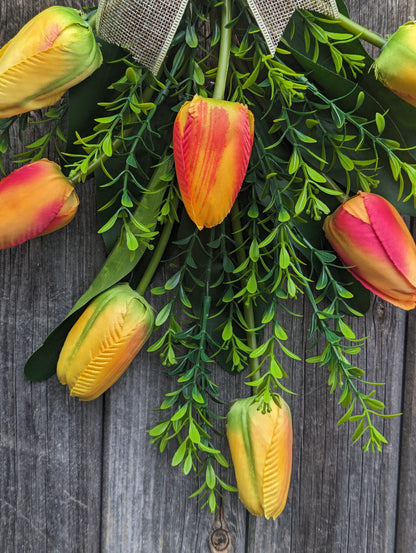 Artificial yellow and orange tulip door swag with tealeaf foliage finished with a hessian bow.