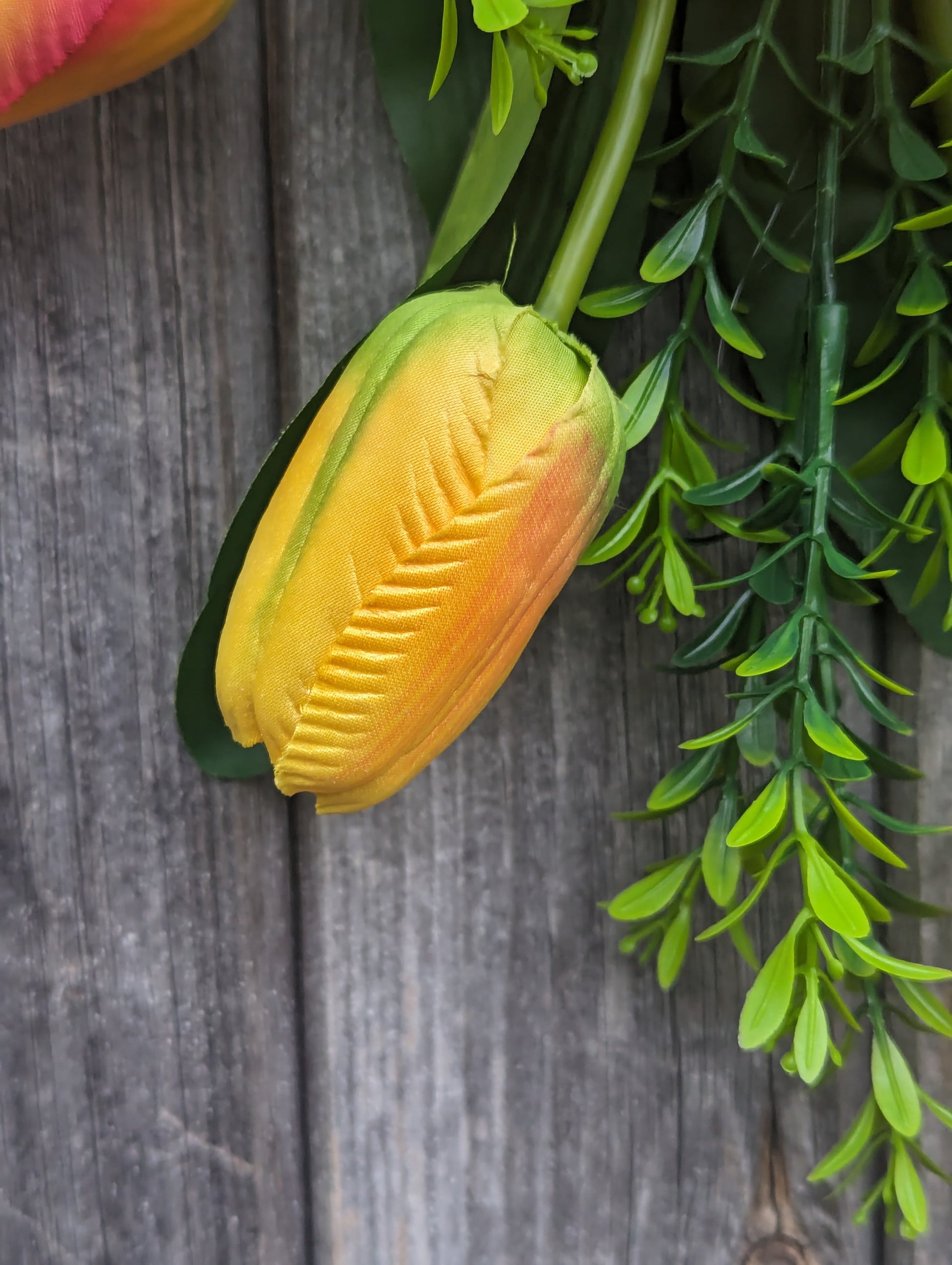 Artificial yellow and orange tulip door swag with tealeaf foliage finished with a hessian bow.